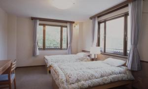 2 camas en una habitación con 2 ventanas en Petit Hotel Shitaka en Hakuba