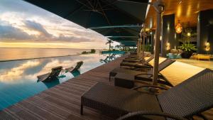 una piscina en un complejo con sillas y sombrillas en The Reef Island Resort Mactan, Cebu en Isla de Mactán