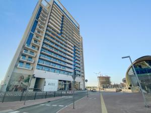 a tall building in a parking lot next to a street at Fully Furnished Studio - 70m from Metro Station in Dubai