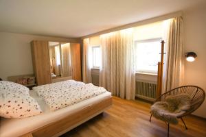 a bedroom with a bed and a chair and a window at Ferienwohnung Alpenblume Königssee in Schönau am Königssee