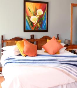 uma cama com almofadas laranja e um quadro na parede em Top House Bed and Breakfast em Ladybrand