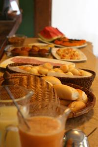 a table topped with baskets of bread and other foods at Pousada Vila Mundi Itaúnas in Itaúnas