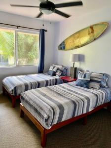 two beds in a room with a surfboard on the wall at The big house - 30 days in Kailua-Kona