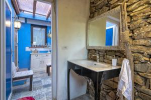 a stone bathroom with a sink and a mirror at Villa Sa Pintadera private pool in Stintino