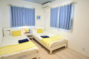 2 łóżka w pokoju z niebieskimi zasłonami w obiekcie Frennch House B022 w mieście Yaka