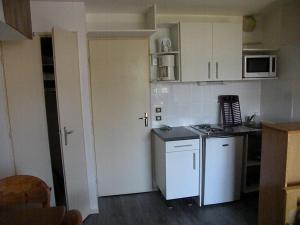 a small kitchen with white cabinets and a counter at Au Coeur De La Station in Les Deux Alpes