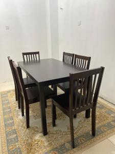 a black dining room table and chairs on a rug at Cik Misi Homestay in Sik