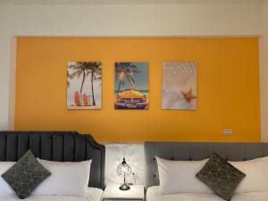 1 dormitorio con pared de color naranja y cuadros encima de la cama en 小路彎彎民宿 鄰近火車站 前庭有停車位, en Taitung 16 fotos más