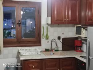 a kitchen with wooden cabinets and a sink and a window at Sunset studios and apartments for Adults over 21 only in Naousa