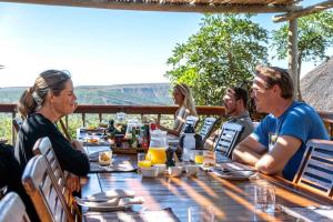 Eine Gruppe von Menschen, die an einem Tisch sitzen und Essen essen. in der Unterkunft Woodbury Lodge – Amakhala Game Reserve in Amakhala Game Reserve