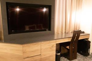 a wooden desk with a television and a lamp at Hotel Massimo Mishima in Mishima