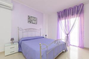 een slaapkamer met een bed en een raam met paarse gordijnen bij Orchidea Casa Vacanze in Trapani