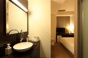 Hotel Massimo Mishima في ميشيما: حمام مع حوض وسرير ومرآة