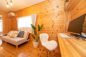 sala de estar con paredes de madera, TV y sofá en Yokkaichi Motomachi Hotel, en Yokkaichi