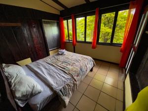 a bedroom with a bed and two windows at Princesa de la Luna Ecolodge in Fortuna