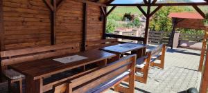 a wooden pavilion with a wooden table and benches at Panoráma Vendégház in Lupeni