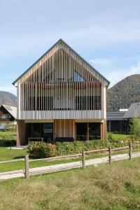 un gran edificio de madera con una valla delante en Residence Novak Bohinj, en Bohinj