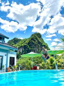 a man jumping into a swimming pool in front of a mountain at Phong Nha Green Homestay in Phong Nha