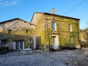 una vieja casa de piedra con hiedra creciendo en ella en Authentiek landhuis met zwembad in Dordogne., 