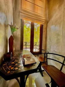 a dining room with a table and a window at Hern Lhin Natural Resort in Ban Pong