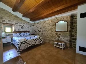 1 dormitorio con cama y pared de piedra en Cal Sastre, en Olíus