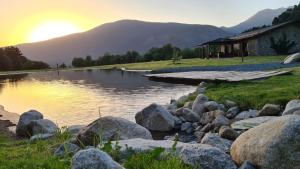 un lago con rocas frente a una casa en Les Pardines 1819 Mountain suites & SPA en Encamp