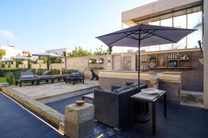 a patio with an outdoor bar with an umbrella at Maison Boutique At in San Pietro in Lama
