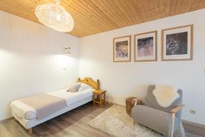 1 dormitorio con 1 cama y 1 silla en La Charbonnière, grand gîte haut-de-gamme avec jacuzzi et sauna, en Gérardmer