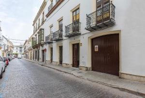 una calle adoquinada con edificios y coches aparcados en la calle en Palacete Centro estilo Luxe, en Jerez de la Frontera