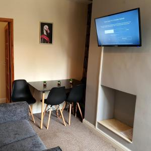a living room with a table and a television on a wall at Newcastle Park House in Stoke on Trent