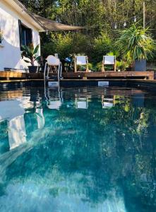 - une piscine avec 2 chaises dans l'eau dans l'établissement Villa avec piscine, terrasse, jardin et vue…, à Bort-les-Orgues