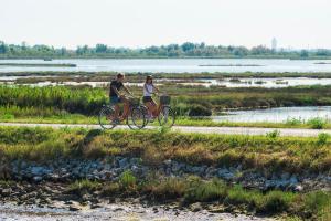 a man and woman riding bikes on a dirt road at Kya Venice and Beach House: Venezia, mare e laguna in Cavallino-Treporti
