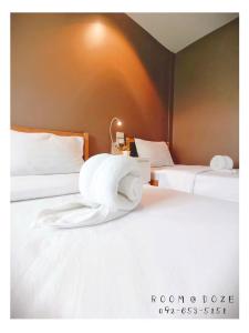 2 camas con sábanas blancas y toallas. en Room@Doze, en Nonthaburi