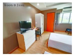um quarto com uma cama e uma secretária com uma televisão em Room@Doze em Nonthaburi