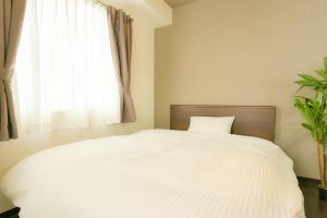a bedroom with a white bed with a window at SUNCORT 南6条Ⅱ in Sapporo