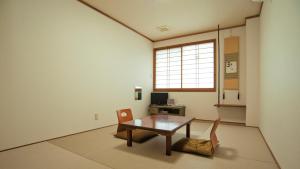 a room with a table and two chairs and a window at Ryokan Urashima in Onomichi