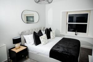 um quarto branco com uma cama com almofadas pretas e brancas em Crieff House em Crieff