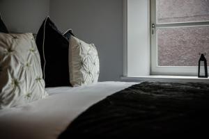 a bed with black and white pillows and a window at Crieff House in Crieff