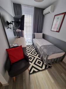 a small bedroom with a bed and a chair at Motel Via Targu Mures in Cristeşti