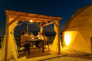a group of people sitting at a table under a pergola at night at Blissful Garden - Vacation STAY 46369v in Shibukawa