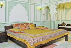 um quarto com uma cama grande e almofadas coloridas em Rani Mahal Hotel em Jaipur