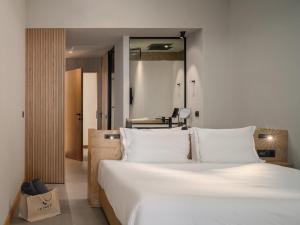 - une chambre avec un grand lit blanc et un miroir dans l'établissement Ikones Seafront Luxury Suites, à Réthymnon