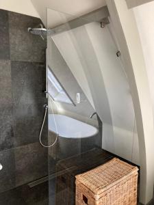 a bathroom with a shower and a wicker stool at Koetshuis aan het water 3 bedroom villa in Voorburg