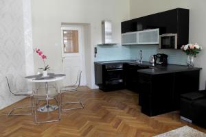 eine Küche mit schwarzen Schränken und einem Tisch mit Stühlen in der Unterkunft Royal Prague Apartment Celakovskeho Sady in Prag