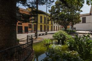 拉古納的住宿－Los Adelantados El Aljibe Live Canarias，黄色建筑前方带池塘的庭院