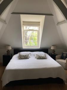 1 dormitorio con 1 cama blanca grande y ventana en Koetshuis aan het water 3 bedroom villa en Voorburg