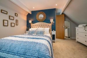 a bedroom with a large bed with a blue wall at Pilgrim Cottage in Tarvin