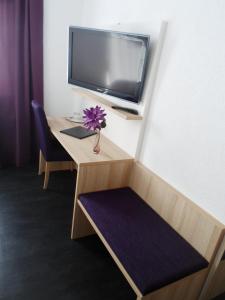 a room with a desk with a tv and a flower at Hotel am Stadtrand in Ostfildern