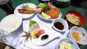 a table topped with plates of food and dipping sauce at Ryokan Urashima in Onomichi