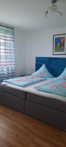 a bed with a blue headboard in a bedroom at Apartment Haus Maria Waldblick in Burtenbach